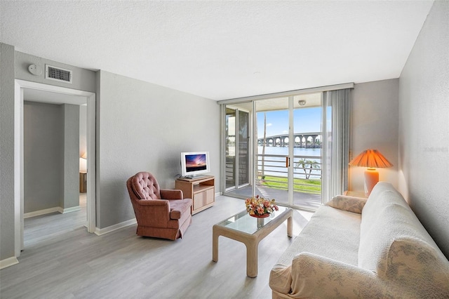 living room featuring a water view, hardwood / wood-style flooring, and a textured ceiling