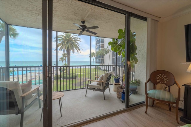 sunroom / solarium featuring ceiling fan and a water view