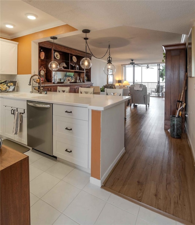 kitchen featuring pendant lighting, light hardwood / wood-style floors, white cabinetry, and stainless steel dishwasher