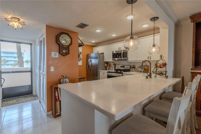 kitchen with kitchen peninsula, hanging light fixtures, stainless steel appliances, light tile flooring, and white cabinetry