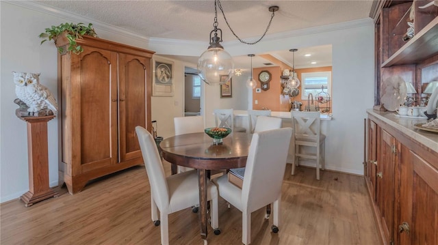 dining space featuring ornamental molding, light hardwood / wood-style flooring, and a textured ceiling