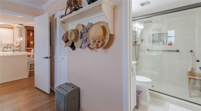 bathroom featuring crown molding, a shower with door, vanity, hardwood / wood-style flooring, and toilet