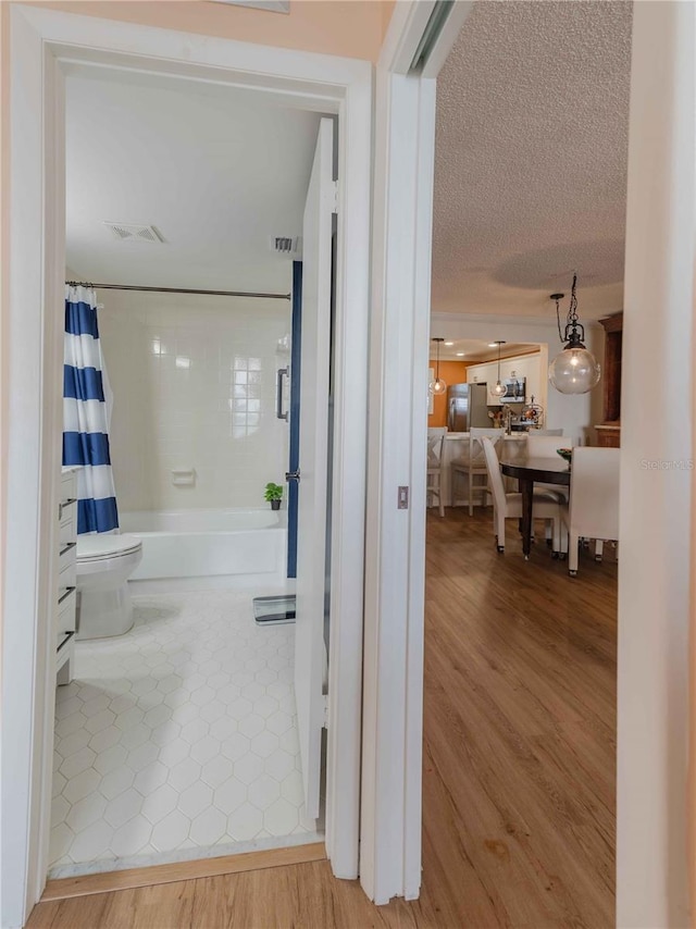 hallway featuring light hardwood / wood-style floors and a textured ceiling