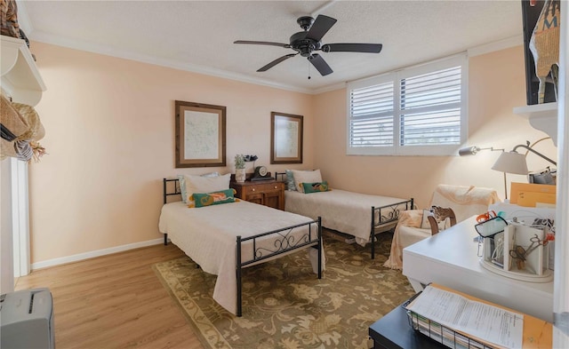 bedroom with hardwood / wood-style flooring, crown molding, ceiling fan, and a textured ceiling