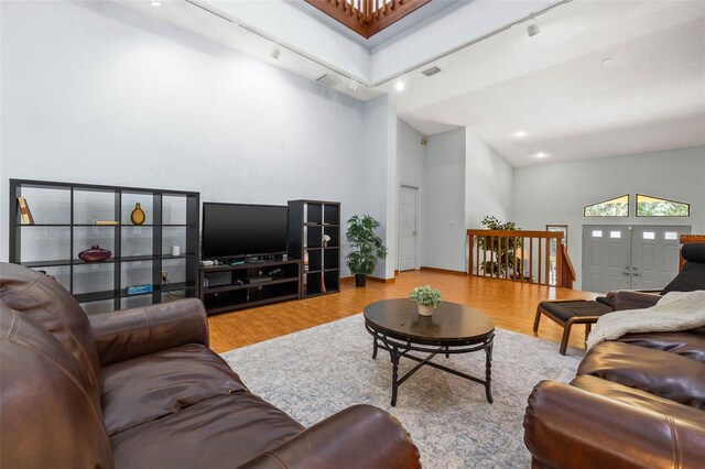 living room with high vaulted ceiling, rail lighting, and hardwood / wood-style flooring