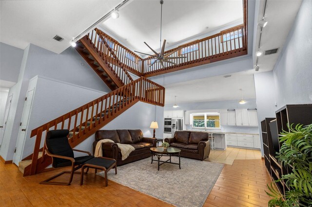 living room with rail lighting, a notable chandelier, light tile floors, and a high ceiling