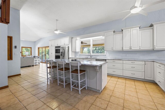 kitchen featuring ceiling fan, a kitchen breakfast bar, white cabinetry, and a kitchen island