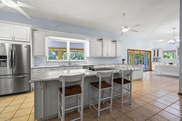 kitchen featuring light tile floors, ceiling fan with notable chandelier, decorative light fixtures, lofted ceiling, and stainless steel refrigerator with ice dispenser