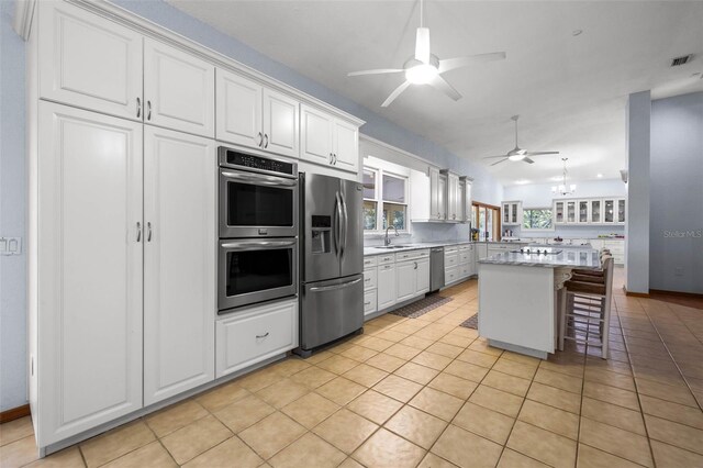 kitchen featuring appliances with stainless steel finishes, plenty of natural light, a kitchen island, and white cabinetry