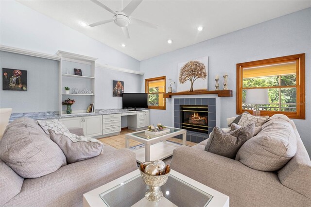 living room with ceiling fan, vaulted ceiling, light tile floors, and a tiled fireplace