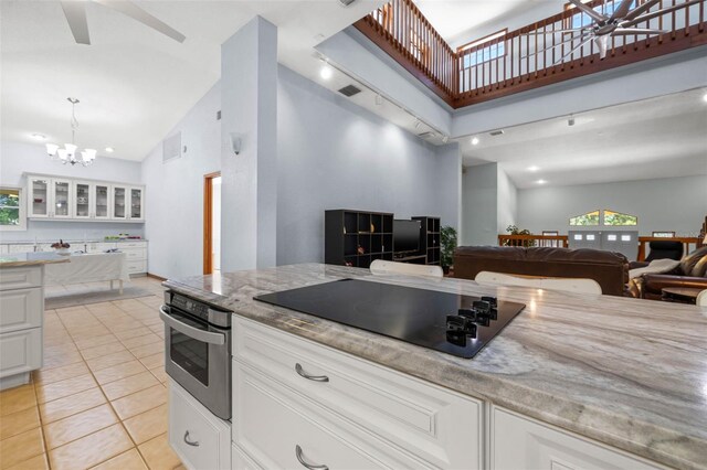 kitchen featuring high vaulted ceiling, oven, black electric stovetop, and white cabinets