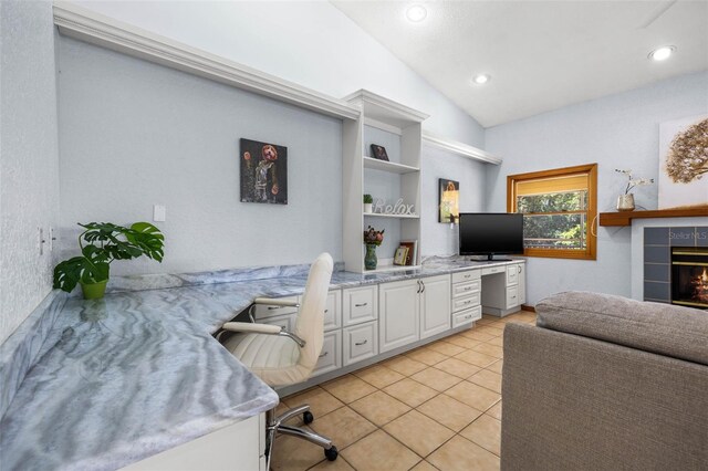 tiled office space featuring vaulted ceiling and a tile fireplace