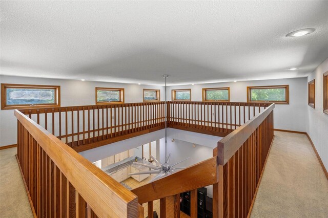 hallway featuring light colored carpet and a textured ceiling