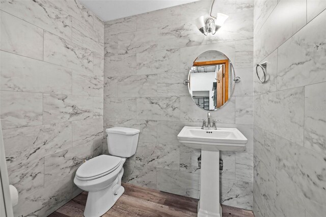 bathroom featuring sink, wood-type flooring, tile walls, and toilet