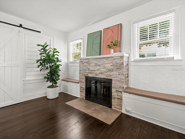 unfurnished living room with a barn door, dark hardwood / wood-style flooring, and a fireplace