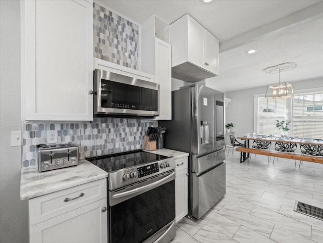 kitchen with light stone counters, tasteful backsplash, white cabinetry, stainless steel appliances, and pendant lighting