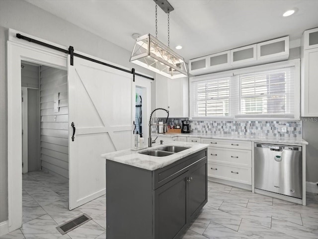 kitchen with a barn door, hanging light fixtures, dishwasher, white cabinets, and sink