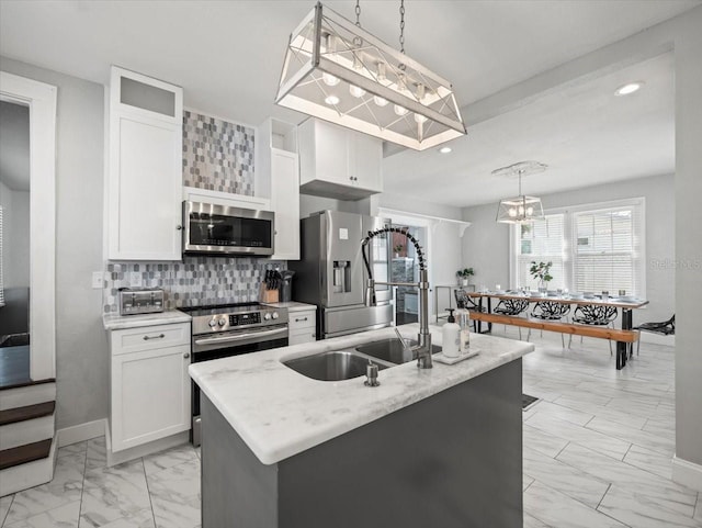 kitchen with decorative light fixtures, appliances with stainless steel finishes, an island with sink, and tasteful backsplash