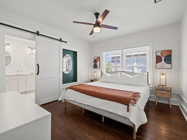 bedroom featuring ensuite bathroom, ceiling fan, a barn door, and dark wood-type flooring