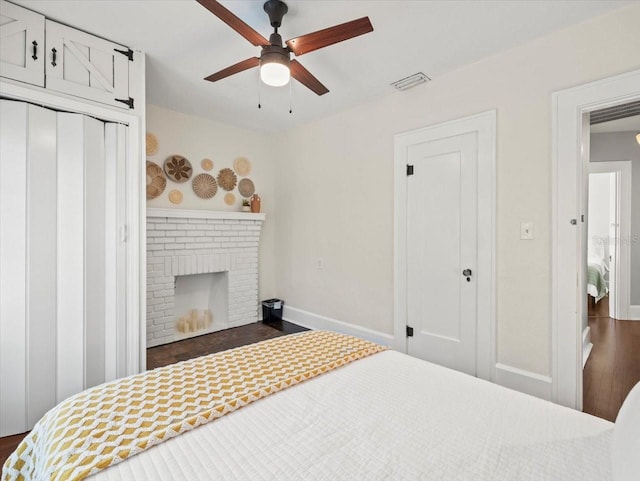 bedroom featuring ceiling fan, a brick fireplace, and dark hardwood / wood-style floors