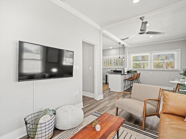 living room featuring ornamental molding, wood-type flooring, and ceiling fan