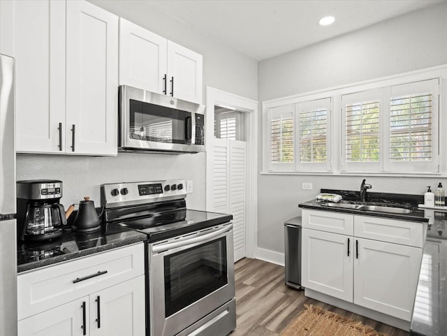 kitchen featuring hardwood / wood-style flooring, appliances with stainless steel finishes, white cabinetry, and sink