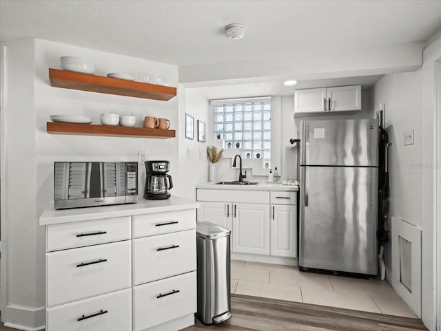 bar with white cabinetry, stainless steel appliances, light tile floors, and sink