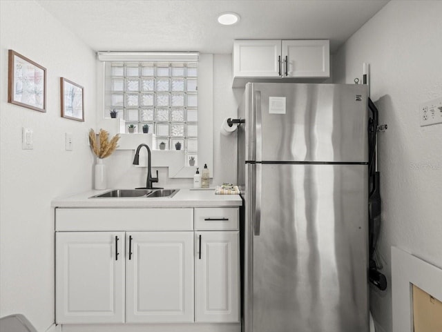 kitchen featuring white cabinets, sink, and stainless steel fridge