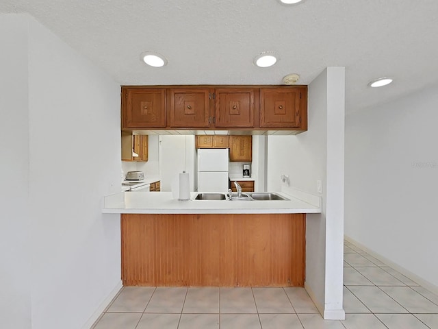 kitchen with kitchen peninsula, white refrigerator, and light tile patterned flooring