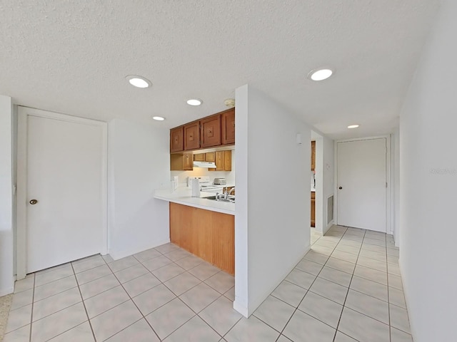 kitchen featuring electric stove, sink, light tile patterned floors, and a textured ceiling