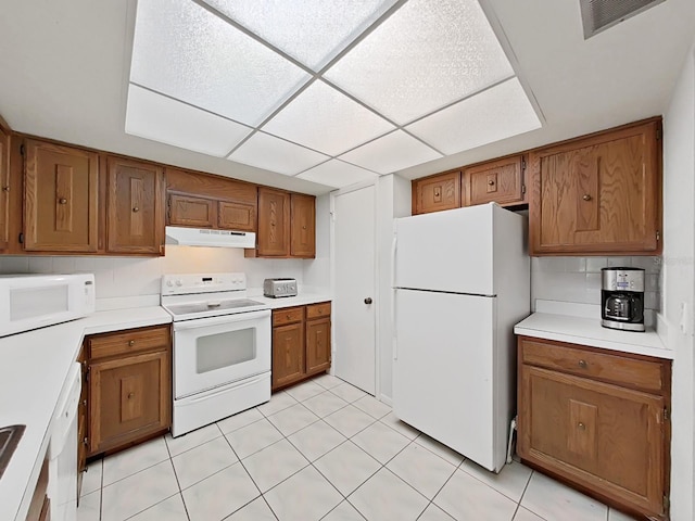 kitchen with a drop ceiling, light tile patterned floors, and white appliances