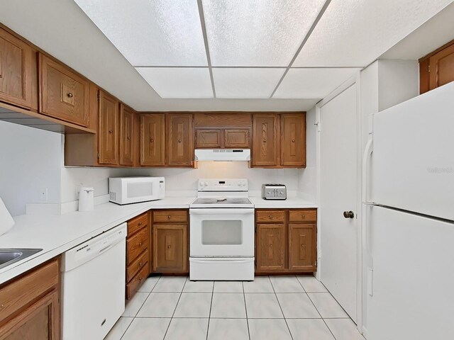 kitchen with a drop ceiling, light tile patterned floors, and white appliances