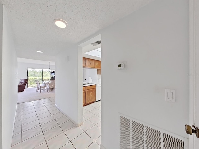 hallway featuring light tile patterned floors and a textured ceiling