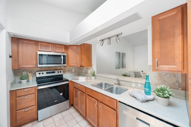 kitchen with backsplash, stainless steel appliances, rail lighting, and light tile patterned floors