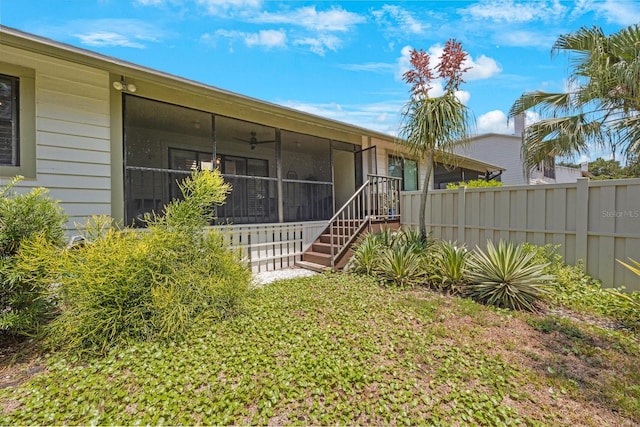 back of house featuring a sunroom, fence, and stairway