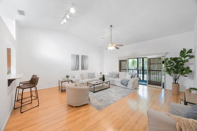 living room with ceiling fan, rail lighting, light hardwood / wood-style floors, and high vaulted ceiling