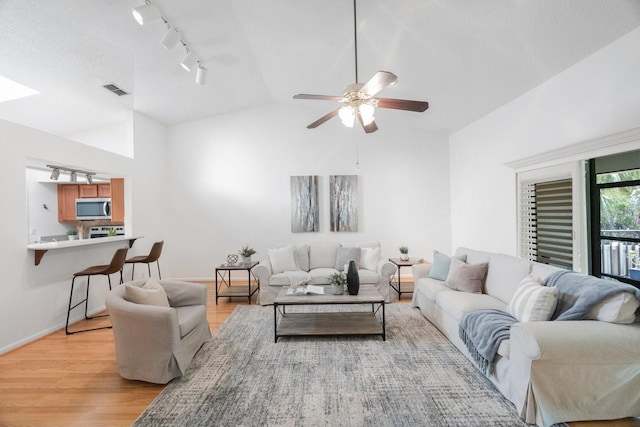 living room with visible vents, a ceiling fan, lofted ceiling, light wood-type flooring, and track lighting