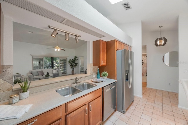 kitchen featuring open floor plan, hanging light fixtures, stainless steel appliances, light countertops, and a sink