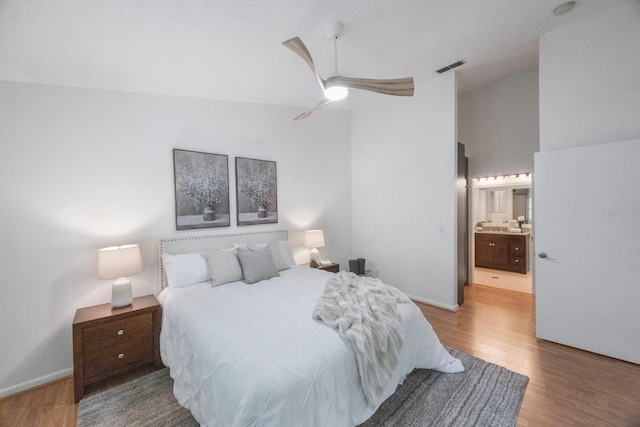 bedroom featuring ceiling fan, connected bathroom, high vaulted ceiling, and wood-type flooring