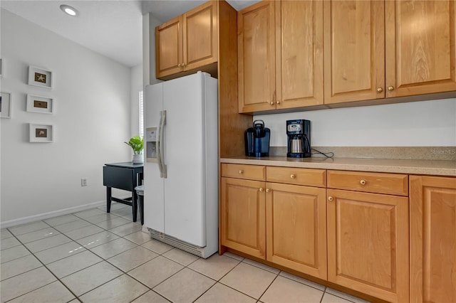 kitchen with white refrigerator with ice dispenser, light tile patterned floors, light countertops, and baseboards
