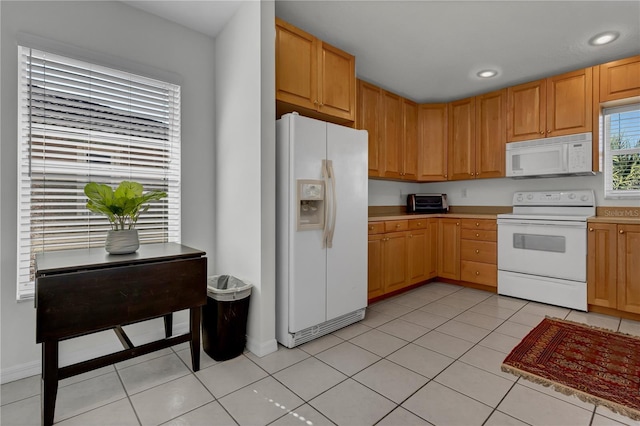 kitchen with white appliances, light tile patterned floors, and light brown cabinets