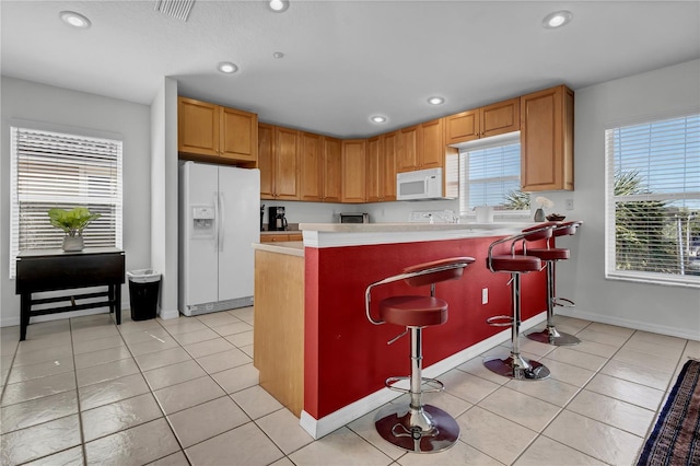 kitchen featuring a kitchen breakfast bar, fridge, and light tile patterned floors