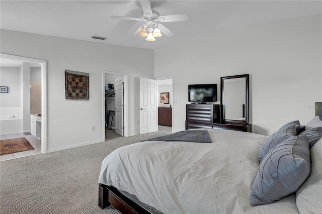 bedroom with ceiling fan, a walk in closet, light carpet, connected bathroom, and lofted ceiling