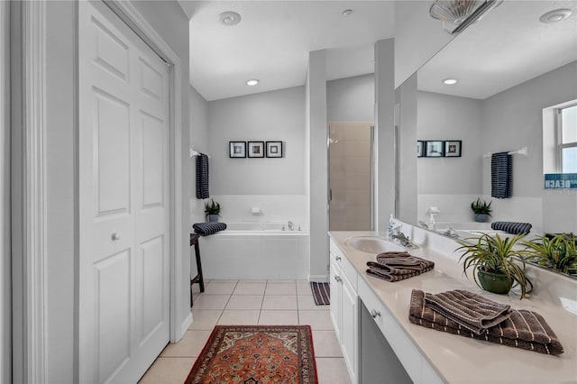 bathroom with a relaxing tiled tub, tile patterned floors, and vanity