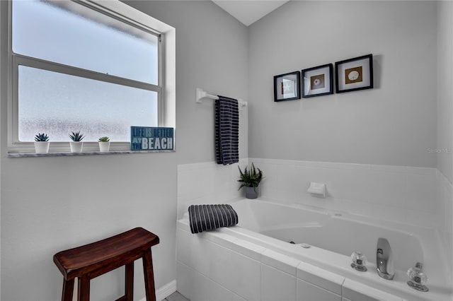 bathroom featuring a wealth of natural light and tiled bath