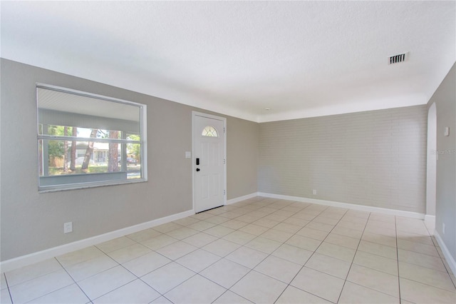 unfurnished room featuring a textured ceiling and light tile floors