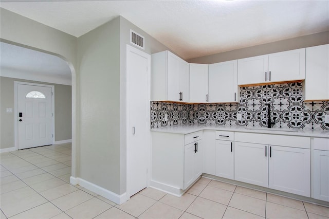 kitchen with backsplash, white cabinets, sink, and light tile flooring