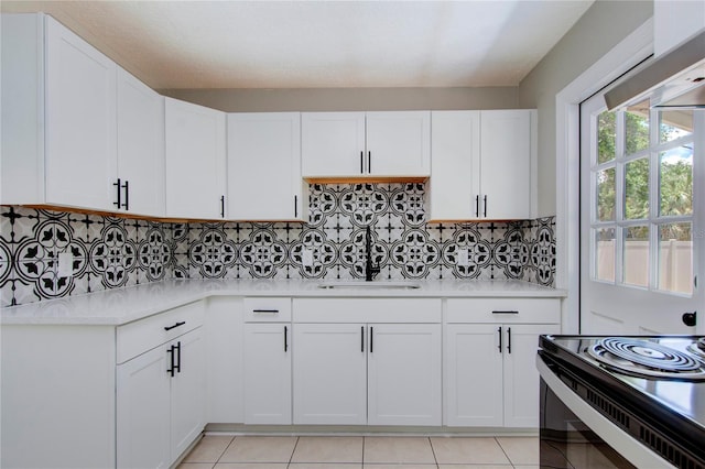 kitchen with white cabinets, backsplash, and light tile floors