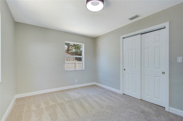 unfurnished bedroom with light carpet and a closet