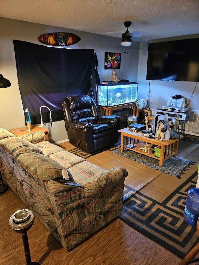 living room with hardwood / wood-style flooring, ceiling fan, and a textured ceiling